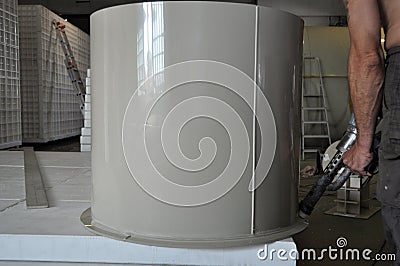 Male worker is sealing a cylindrical custom made plastic tank at the small manufacturing Stock Photo