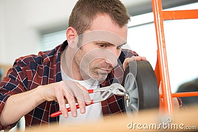 male worker trying to fix trolley wheels Stock Photo