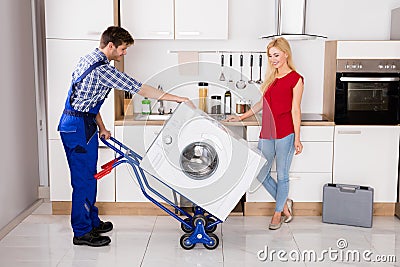 Male Worker Using Hand Truck For Carrying Washer In Kitchen Stock Photo