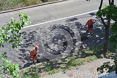 male workers clean the road after repairing it Editorial Stock Photo