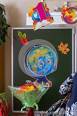 Classroom decorated for September 1st: drawing of a globe on a chalkboard and a bouquet of flowers, blur effect. Editorial Stock Photo