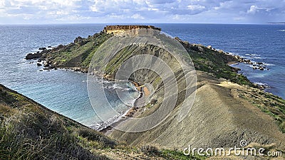 Malta island, near of golden bay, sea coast erosion, grey gravel. Gravel and green bush cliff hills. Peninsula in blue sea bay Stock Photo