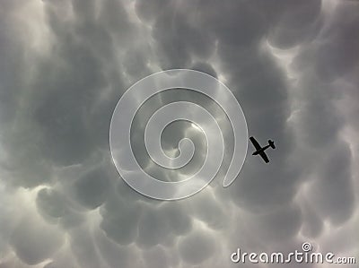 Mammatus Dark Storm Clouds and Lite Plane Stock Photo