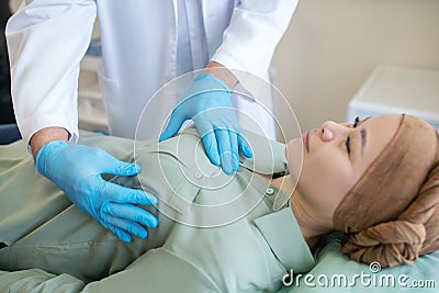 Mammologist in blue protective gloves palping breast of his patient Stock Photo