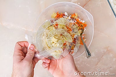 A man adds frozen cabbage to the minced meat for lazy cabbage rolls on the table. Stock Photo