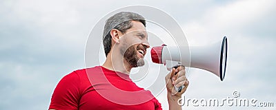 man advertiser in red shirt shout in loudspeaker on sky background Stock Photo