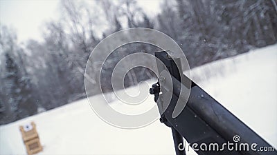 A man aiming a pellet gun towards a target, practicing his aim in the winter. Clip. The shooter in camouflage targets a Stock Photo