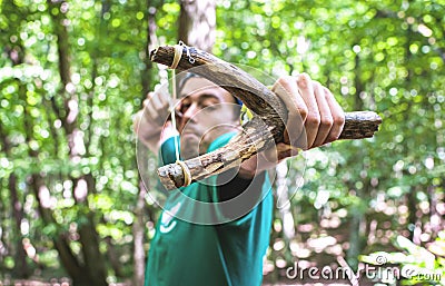 The man aims a slingshot in the camera lens. Stock Photo