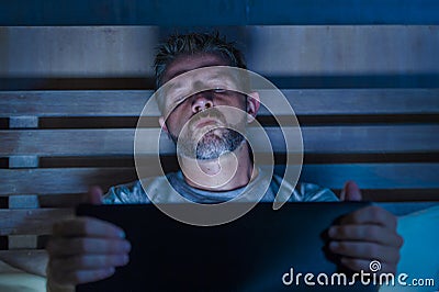 Man alone in bed playing cybersex using laptop computer watching sex movie late at night with lascivious pervert face Stock Photo