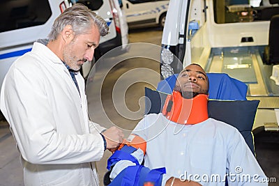 Man on ambulance stretcher wearing neck and arm brace Stock Photo