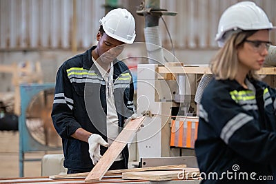 Man American African wearing safety uniform and hard hat working quality inspection of wooden products at workshop manufacturing Stock Photo