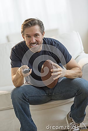 Man With American Football Watching TV Stock Photo