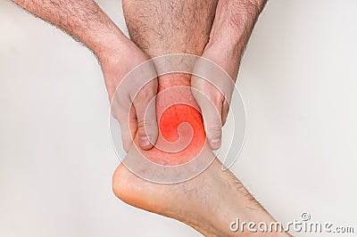 Man with ankle pain holding his aching leg Stock Photo