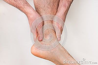 Man with ankle pain holding his aching leg Stock Photo