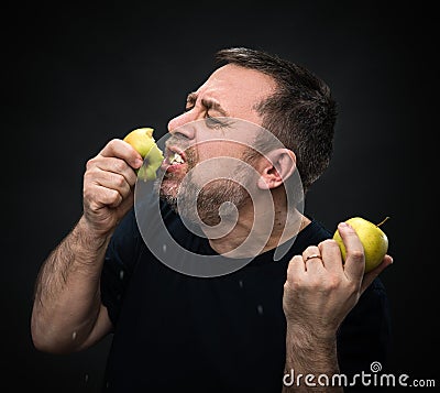 Man with an appetite eating a green apple Stock Photo