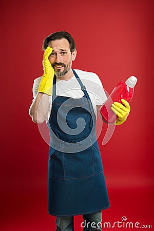 Man in apron with gloves hold plastic bottle liquid soap chemical cleaning agent. Cleaning day today. Bearded guy Stock Photo