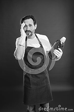 Man in apron with gloves hold plastic bottle liquid soap chemical cleaning agent. Cleaning day today. Bearded guy Stock Photo