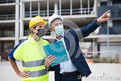 Man architect and a young woman engineer in masks discussing a construction project Stock Photo