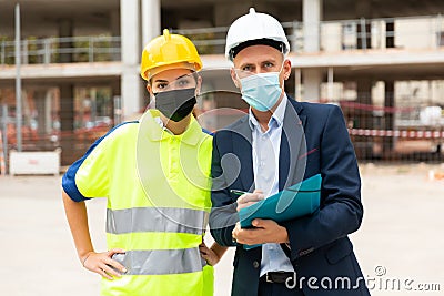 Man architect and a young woman engineer in masks discussing a construction project Stock Photo