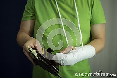 A man with an arm in a cast counted out money from the cost and expenses of emergency medical care at the hospital . Stock Photo