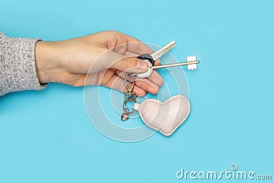 Man arm out holding new key give blue background two heart keychain hand love flat apartment with togather Stock Photo