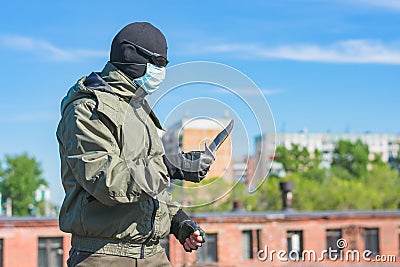 Man armed with a knife in a balaclava, black glasses and a medical mask Stock Photo