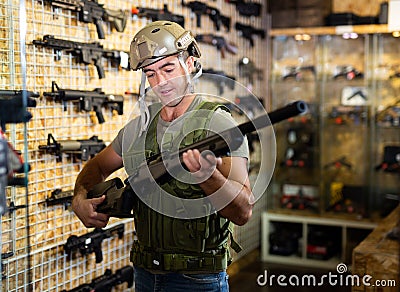 Man choosing rifle in airsoft shop Stock Photo