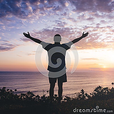 Man with arms outstretched celebrating in beautiful inspiring sunset Stock Photo