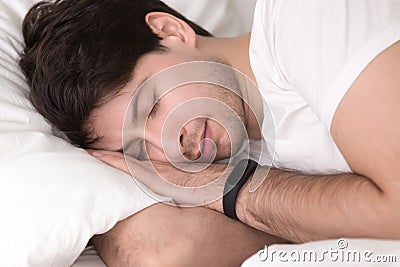 Man asleep in bed wearing smart wristband for sleep tracking Stock Photo