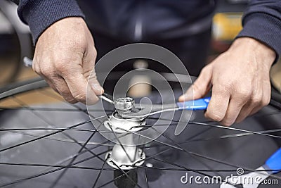 Man assembling a bike wheel axle as part of a bicycle maintenance service Stock Photo