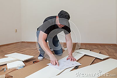 Man dressed casual assembling furniture in new house. Carpenter repair and assembling furniture at home Stock Photo