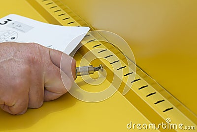 Man assembling a yellow metal cabinet with a screwdriver and instructions. Self assembly furniture concept Stock Photo