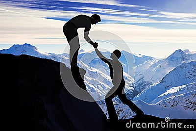 Man Assisting Male Friend In Climbing Rock Stock Photo