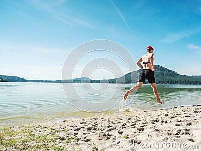 Bare foots runner run in water just in black shorts Stock Photo
