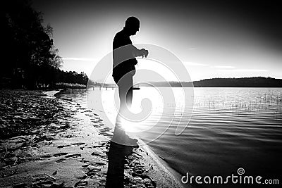 Man checking time during workout run exercise outdoors at ocean beach in sunny cold morning. Runner in sportswear Stock Photo