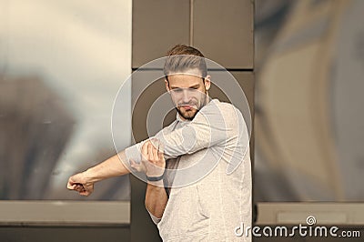 Man athlete concentrated face stretching arms before workout, urban background. Runner stretching training outdoor Stock Photo