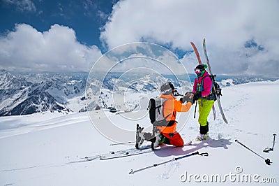 A man athlete skier freerider makes a proposal to marry his woman skier high in the mountains in winter. against the Stock Photo