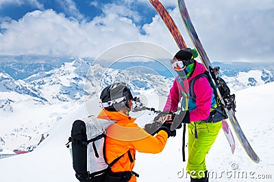 A man athlete skier freerider makes a proposal to marry his woman skier high in the mountains in winter. against the Stock Photo