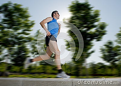 Man with athletic legs running in city park with trees on the background on summer training session fitness healthy lifestyle Stock Photo