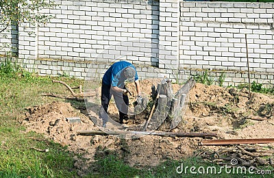 Man with an ax uproots a tree stump Stock Photo
