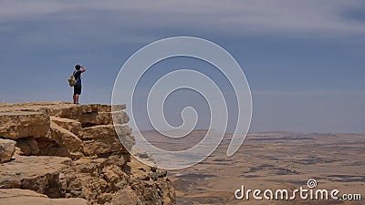 Man with backpack standing on the desert mountain rock cliff edge Stock Photo