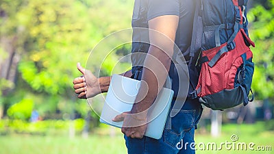 Man with a backpack standing in a park. Backpacker holding a laptop. Digital nomad concept Stock Photo