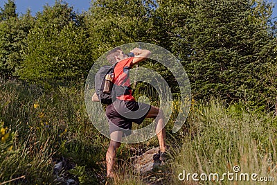 Man with backpack take a rest and drinking from water bottle during a hike Stock Photo