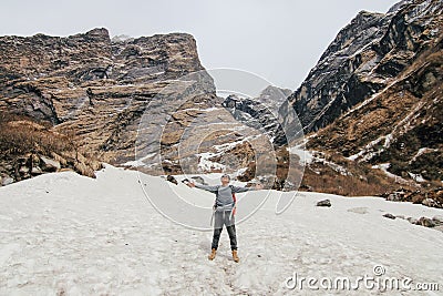 Man with backpack trekking in mountains. Cold weather, snow on hills. Winter hiking. Stock Photo