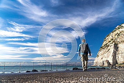 Man with backpack walk alone and watching on the water strong waves, clouds and mountains bacground, Sorrento Italy Editorial Stock Photo