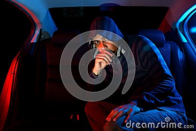 Man in the backseat of a car wearing a hoodie shirt Stock Photo