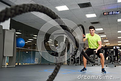 Man with battle ropes exercise in the fitness gym. Stock Photo