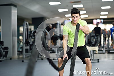 Man with battle ropes exercise in the fitness gym. Stock Photo