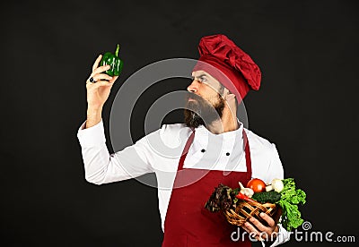 Man with beard on black background looks at pepper. Stock Photo