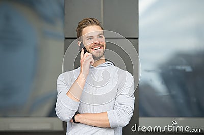 Man with beard call smartphone urban background. Guy happy smile use smartphone to communicate friends. Man use mobile Stock Photo
